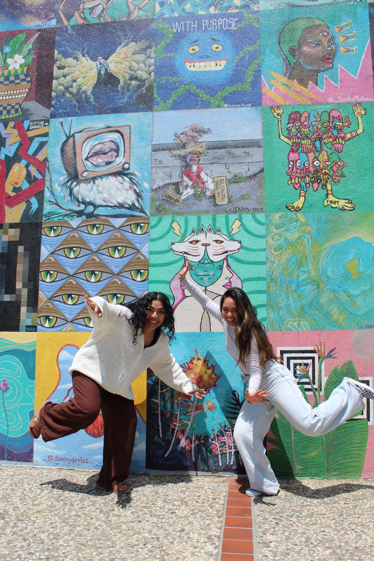 Two vocalists posing playfully in front of a mural wall
