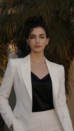 Gabriella Quijada, coach at The Voice Collective Co., in an ivory suit and black blouse, photographed in front of palm fronds